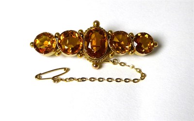 Lot 350 - A citrine brooch, an oval cut citrine in a collet setting, within a rope and beaded border, flanked