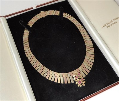 Lot 390 - A 1970s 9 carat tri-colour gold textured link necklace, the front with a ruby set floral...