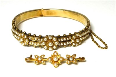 Lot 393 - A seed pearl bangle, two rows of seed pearls with three applied floral clusters, measures 5.3cm...