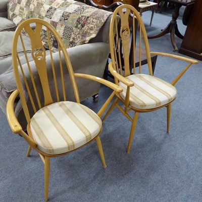 Lot 1063 - A pair of Ercol armchairs with swan carved splat, labels to underside