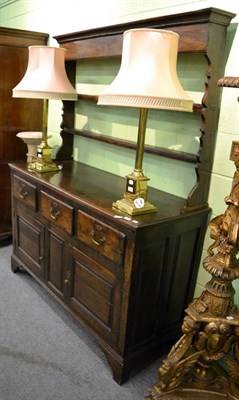 Lot 1145 - An 18th century oak enclosed dresser and rack, with two shelves and shaped end supports, the...