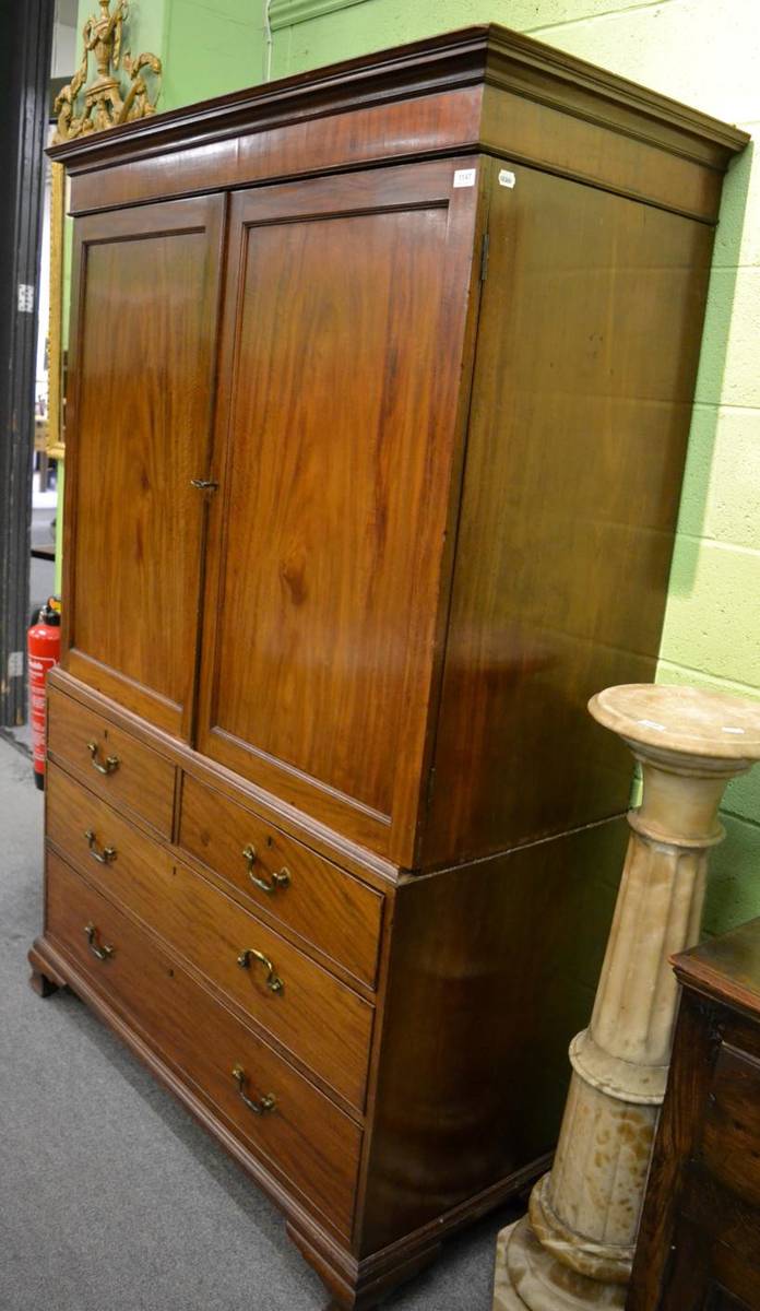 Lot 1147 - A George III mahogany linen press, the upper section containing five slide out trays, on ogee...