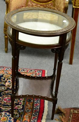 Lot 1181 - A circular glazed bijouterie table with hinge top and four supports joined by an under tier