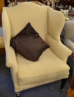 Lot 1209 - A wing armchair re-covered in designers guild fabric, with a purple cushion