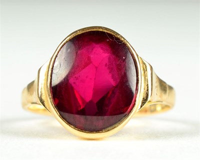 Lot 72 - A synthetic ruby ring, a round mixed cut synthetic ruby in a rubbed over setting, to tapered...