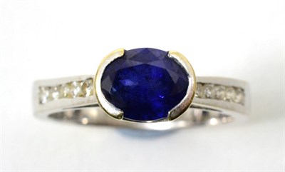 Lot 83 - A sapphire and diamond ring, an oval cut sapphire in a half rubbed over setting, to tapering...