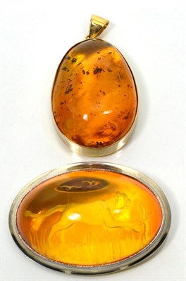 Lot 104 - An amber intaglio brooch, an oval cabochon amber carved depicting a running lioness amongst...
