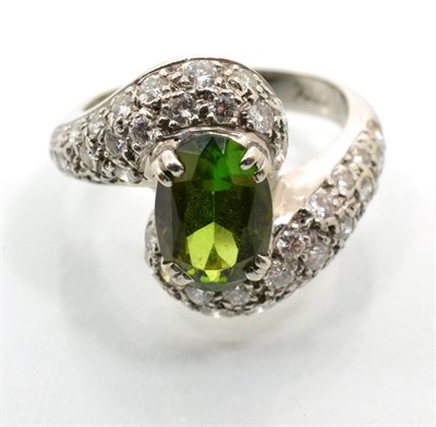 Lot 116 - A green tourmaline and diamond twist ring, an oval cut green tourmaline in a claw setting, to pavé