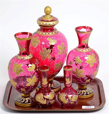 Lot 281 - A group of gilt decorated cranberry glass vases, comprising; a pair of vases; a vase and cover; and