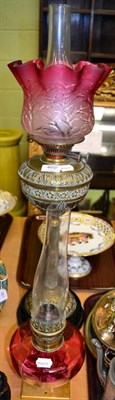 Lot 460 - A Victorian brass oil lamp with cranberry shade and a cranberry glass oil lamp reservoir on a later