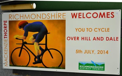 Lot 1150 - After Mackenzie Thorpe, an advertising sign for the 2014 Tour de Yorkshire for Richmondshire...