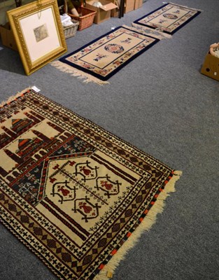 Lot 1360 - A Balouch prayer rug, the Mihrab beneath two panels containing mosques enclosed by narrow...