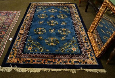 Lot 1365 - A Chinese rug with blue centre woven with roundels, within a peach floral border 245cm by 166cm