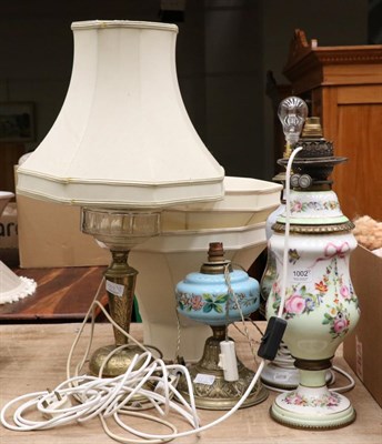 Lot 1002 - A floral painted opaline glass oil lamp, converted to electricity, another painted glass table lamp