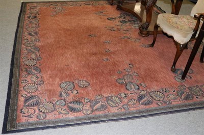 Lot 1293 - A machine made carpet of Chinese design, the coral pink field with pagoda and tree enclosed by...