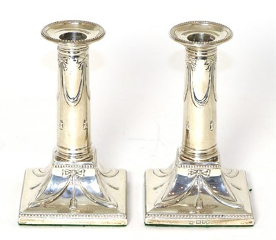 Lot 195 - A pair of late Victorian silver candlesticks of George III style, London, 1900, decorated with...