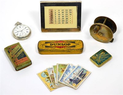 Lot 62 - Brass fishing reel, silver pocket watch, silver calendar, Dunlop tin, Songster tin, Gallaher...