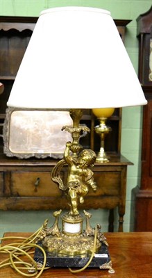 Lot 356 - A gilt metal lamp in the form of a putto with gathered cream shade and marble base