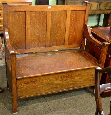 Lot 1246 - An early 20th century Arts & Crafts oak box settle, panelled back, hinged seat, square...