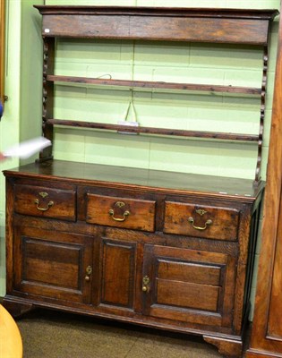 Lot 1311 - An 18th century oak enclosed dresser and rack, with two shelves and shaped end supports, the...