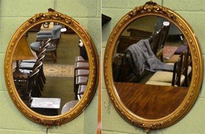 Lot 1324 - A pair of late 19th century gilt gesso oval wall mirrors