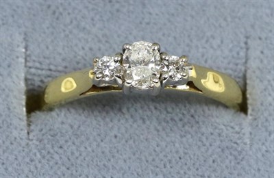 Lot 57 - An 18 carat gold diamond three stone ring, an oval cut diamond between two round brilliant cut...