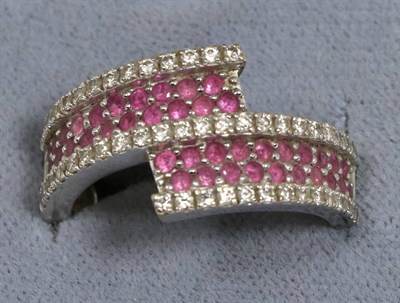 Lot 73 - An 18 carat white gold ruby and diamond crossover ring, two rows of round cut rubies between...