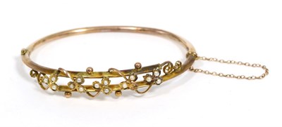 Lot 94 - A seed pearl bangle, the crossover front with a motif of seed pearl set trailing vines, to a...
