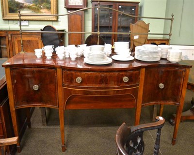 Lot 1263 - A George III mahogany and tulip wood banded serpentine shaped sideboard with brass gallery...