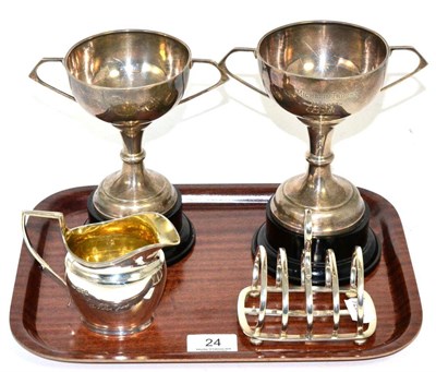 Lot 24 - A silver toast rack, by Hukin and Heath, Birmingham, 1928; with two silver twin handled trophy cups