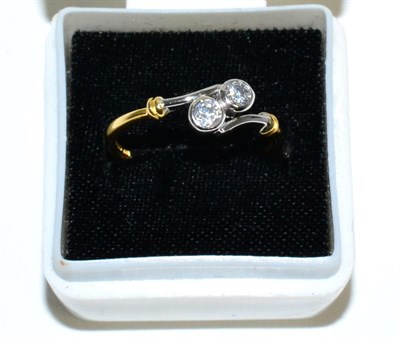 Lot 97 - An 18 carat gold diamond cross over ring, two round brilliant cut diamonds in rubbed over settings