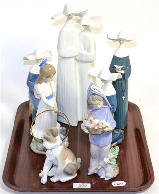 Lot 255 - Six Lladro figures comprising; four nuns, a young girl holding a cat basket, a dog, and a Nao...