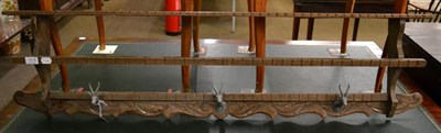 Lot 1216 - A carved wooden coat rack with patinated metal springbok head hangers