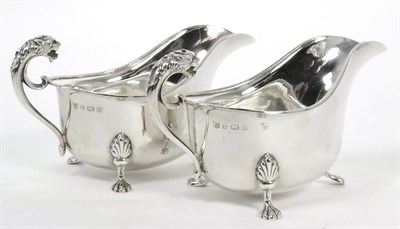 Lot 79 - A pair of silver sauce boats, Barker Bros, Birmingham 1932, with lion mask handles, 15cm long,...