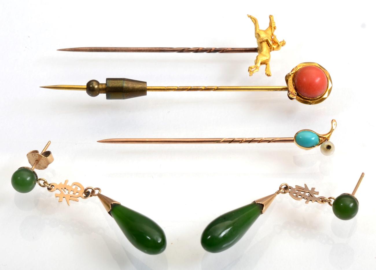 Lot 118 - An equestrian stickpin, modelled as a jockey on horseback; a coral stickpin, within a coiled...