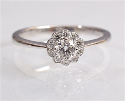Lot 125 - An 18 carat white gold diamond cluster ring, a round brilliant cut diamond within a border...