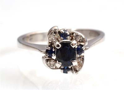 Lot 135 - A sapphire and diamond ring, an oval cut sapphire within a scroll frame of round brilliant cut...