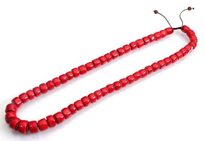 Lot 145 - A dyed red coral necklace, of graduated barrel beads, on a cord strap, length 80cm approximately