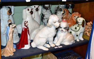 Lot 181 - A shelf of decorative ceramics including three pairs of dogs, a pair of lions, two Nao dogs,...
