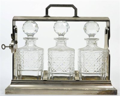 Lot 285 - An electroplated three bottle tantalus, with three square section cut glass decanters