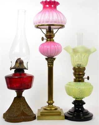 Lot 288 - Three oil lamps comprising a cranberry glass gilt metal oil lamp, a yellow vaseline reservoir...