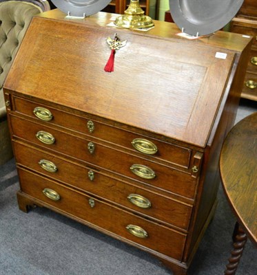 Lot 1338 - A George III oak bureau, on scroll bracket feet