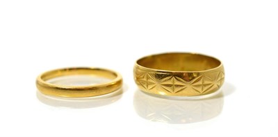 Lot 88 - A 22 carat gold band ring, finger size Q and an 18 carat gold star engraved band ring, finger...