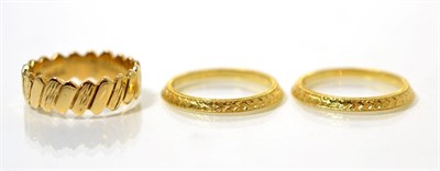 Lot 107 - An 18 carat gold two part band ring, with chased bell husk design, finger size M and a 9 carat gold