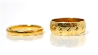 Lot 218 - A 22 carat gold band ring, finger size M1/2 and a 9 carat gold star engraved broad band ring,...