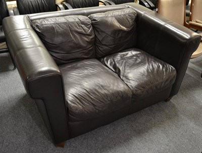 Lot 1167 - A brown leather two-seater sofa, modern, with rounded square form arms and overstuffed seat, raised