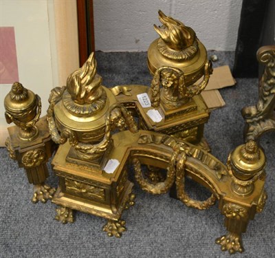 Lot 1223 - A pair of French gilt metal chenets, in Louis XVI style, with flamiform finials issuing from...