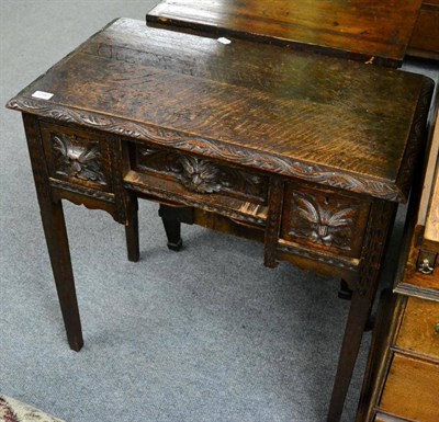 Lot 1290 - A carved oak side table fitted with three drawers, each with lion mask carved handles