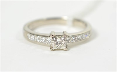 Lot 82 - A platinum princess cut solitaire diamond ring, in a claw setting, to channel set princess cut...