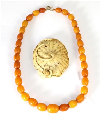 Lot 95 - An amber bead necklace, graduated oval beads knotted to a jump ring, length 44cm and a carved...